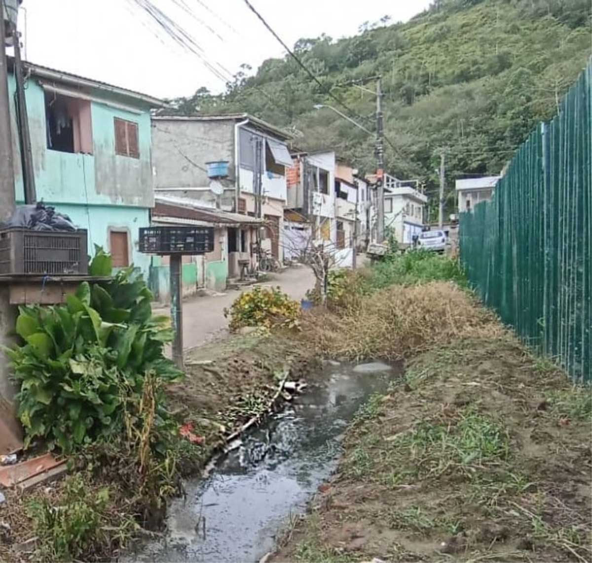 Vila Barreira - mangueiras de captação alternativa de água que abastece a comunidade passando dentro do esgoto. Imagem: Biocasa.